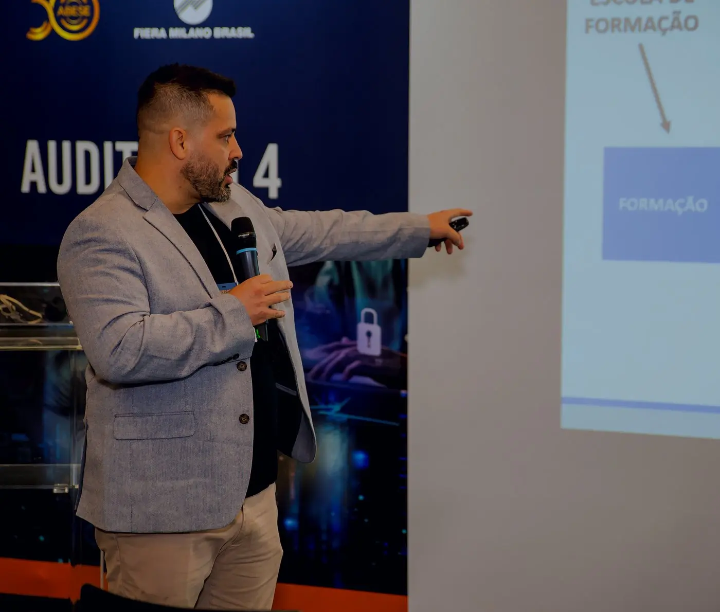 Diego Ferreira apontando para a tela durante uma palestra técnica sobre segurança privada